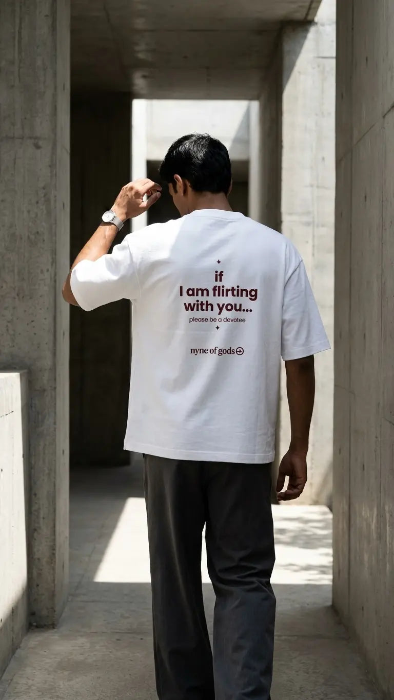 Person wearing a white t-shirt with text, standing in a concrete hallway.